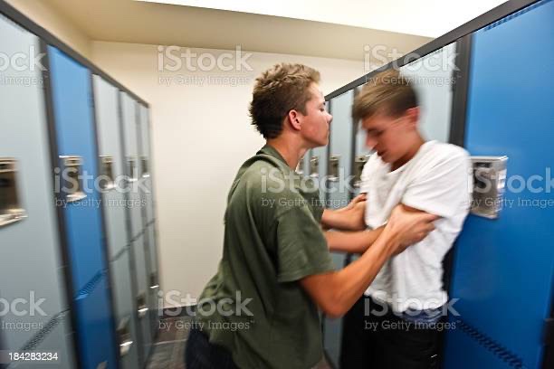 Male student pushing another male student into a school locker